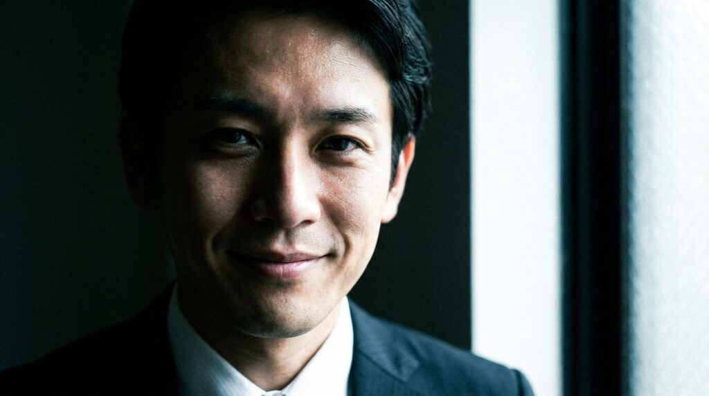 口元は笑っているが目が全く笑っていない日本人男性の顔。意地悪な人の顔つきに見られる典型的な特徴。