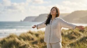 青空の下で風を感じながら解放感に満ちた表情を見せる日本人女性。人に執着しない人の特徴や心理を理解し、執着を手放すことで得られる自由な生き方を象徴している。